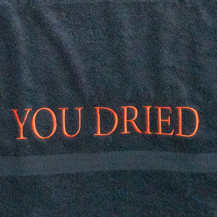 Primo piano delle lettere "YOU DRIED" ricamate in rosso